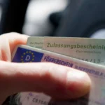 Ein neuer deutscher Karten führerschein kaufen iegt auf einem Schreibtisch neben einem Smartphone mit der Fahrberater-Website.
