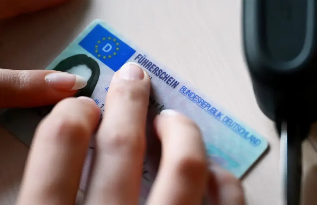Ein glücklicher Fahrschüler sitzt am Steuer eines Fahrschulautos, passend zum Thema Führerschein Preis im Jahr 2026.
